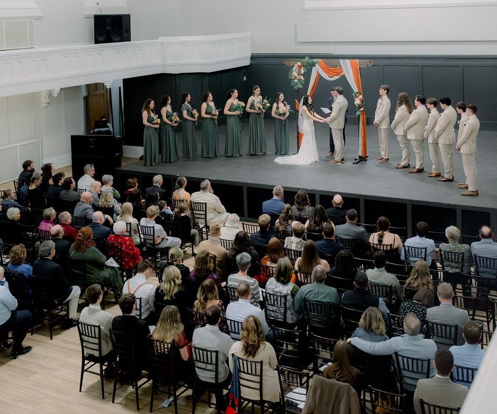 A large room filled with tables and chairs covered in black covers.