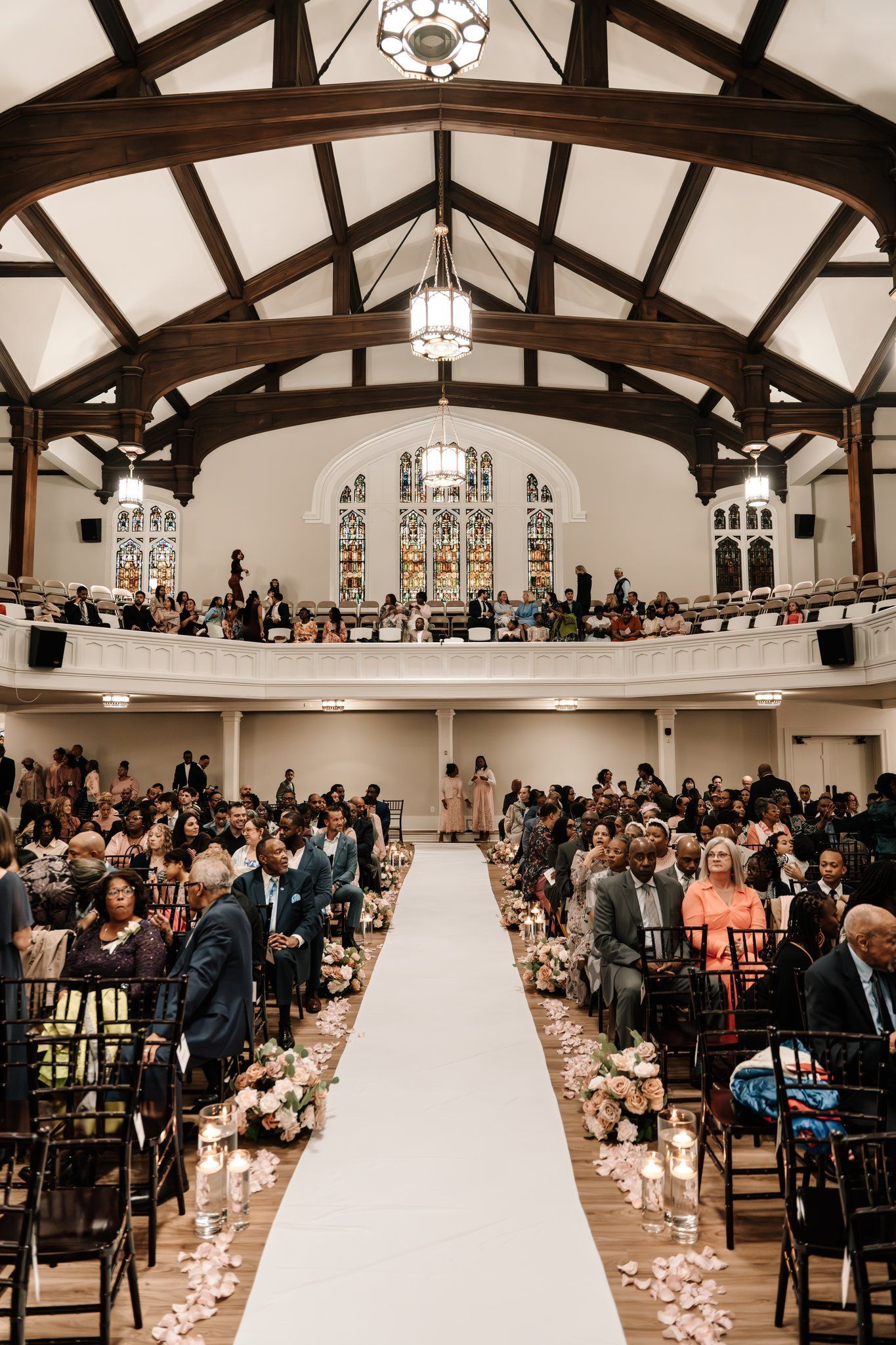 A bride and groom are kissing in a church with stained glass windows.