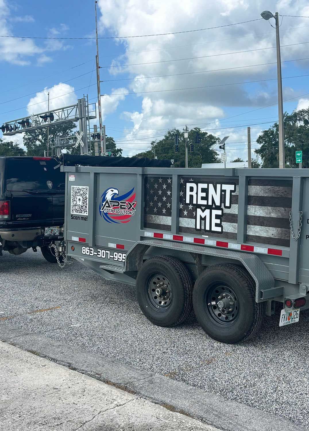 Truck towing a gray dump trailer with an American flag design and 