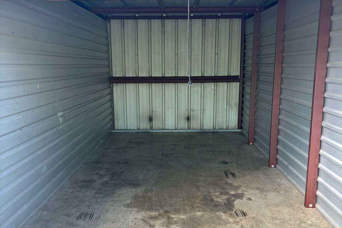 Empty storage unit with metal walls and a closed metal door.