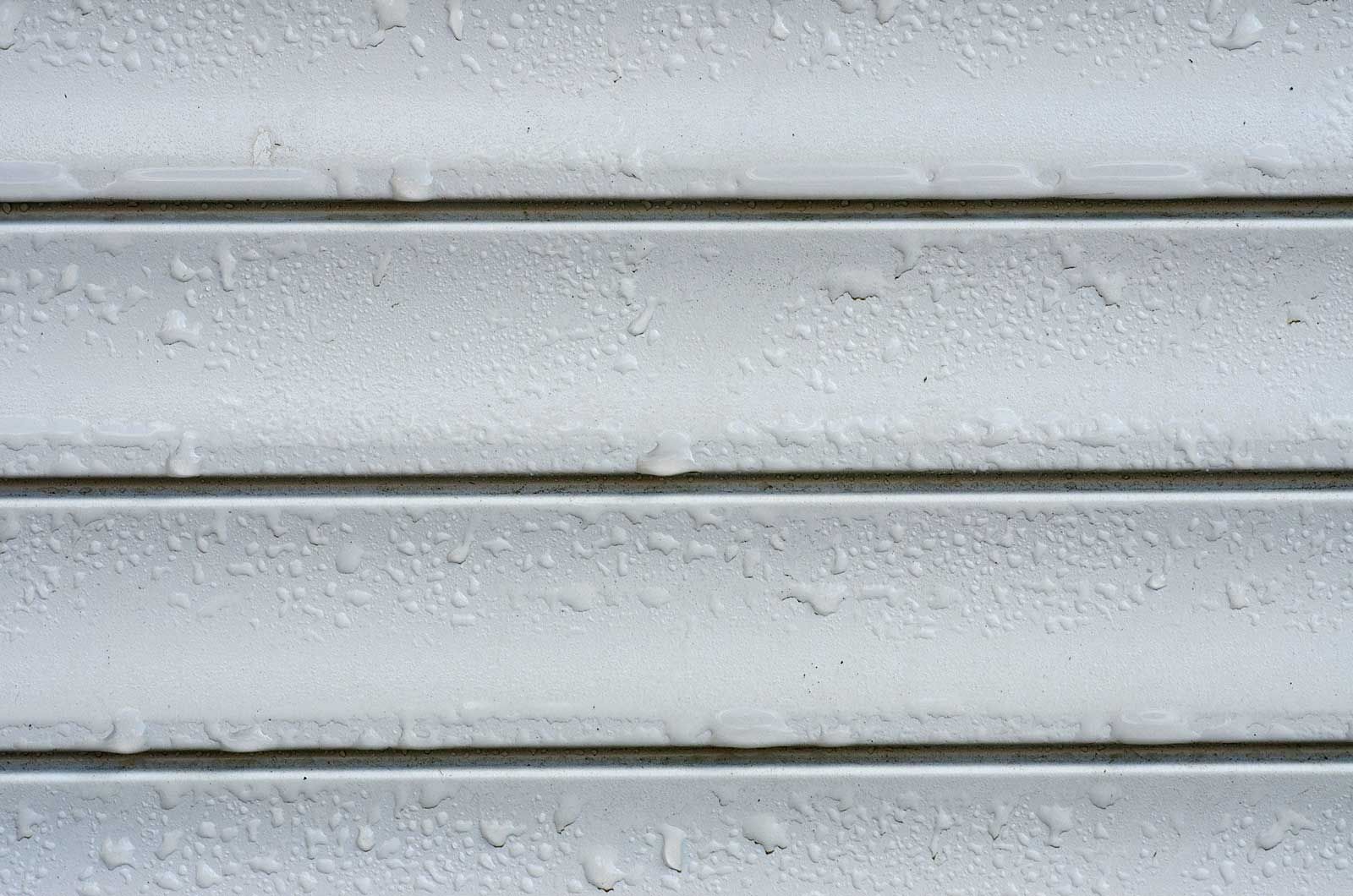 Close-up of a white, horizontally-slatted surface with small water droplets.
