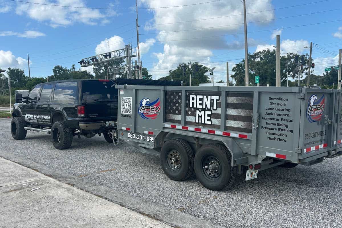 Black truck towing a gray trailer with American flag design and 