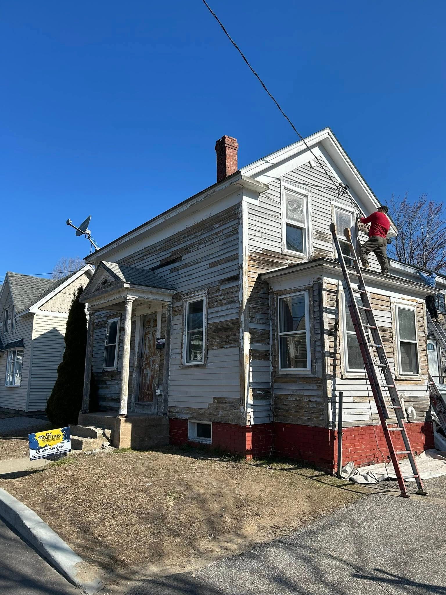 A group of people are painting a large house.