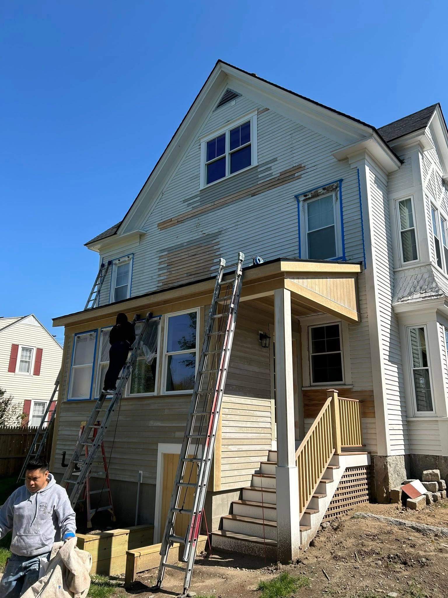 A group of people are painting a large house.