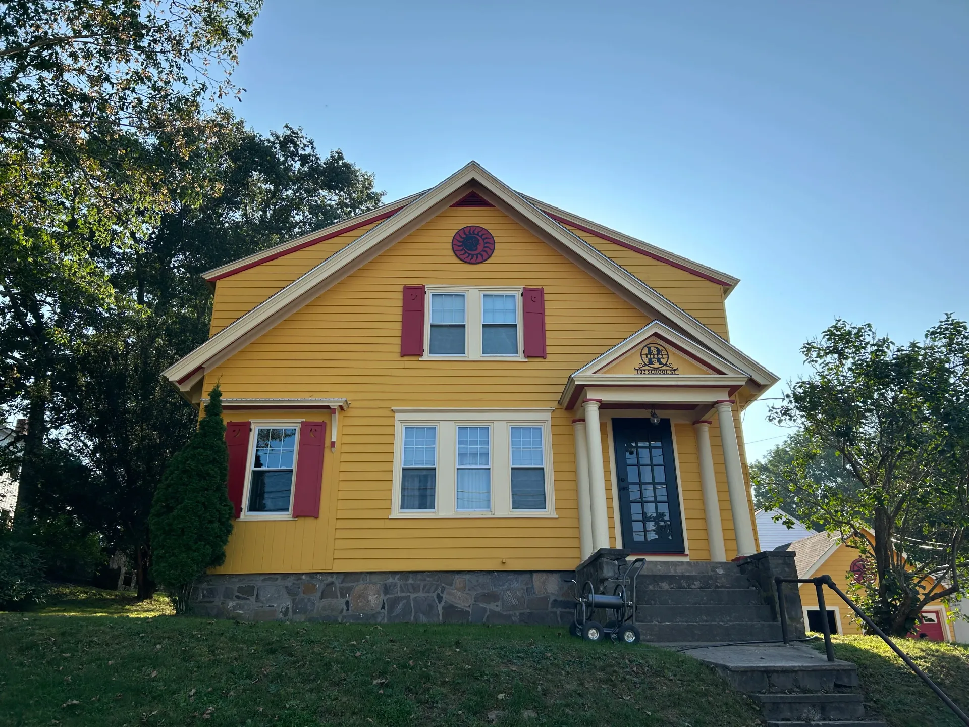 A yellow house with red shutters on the windows