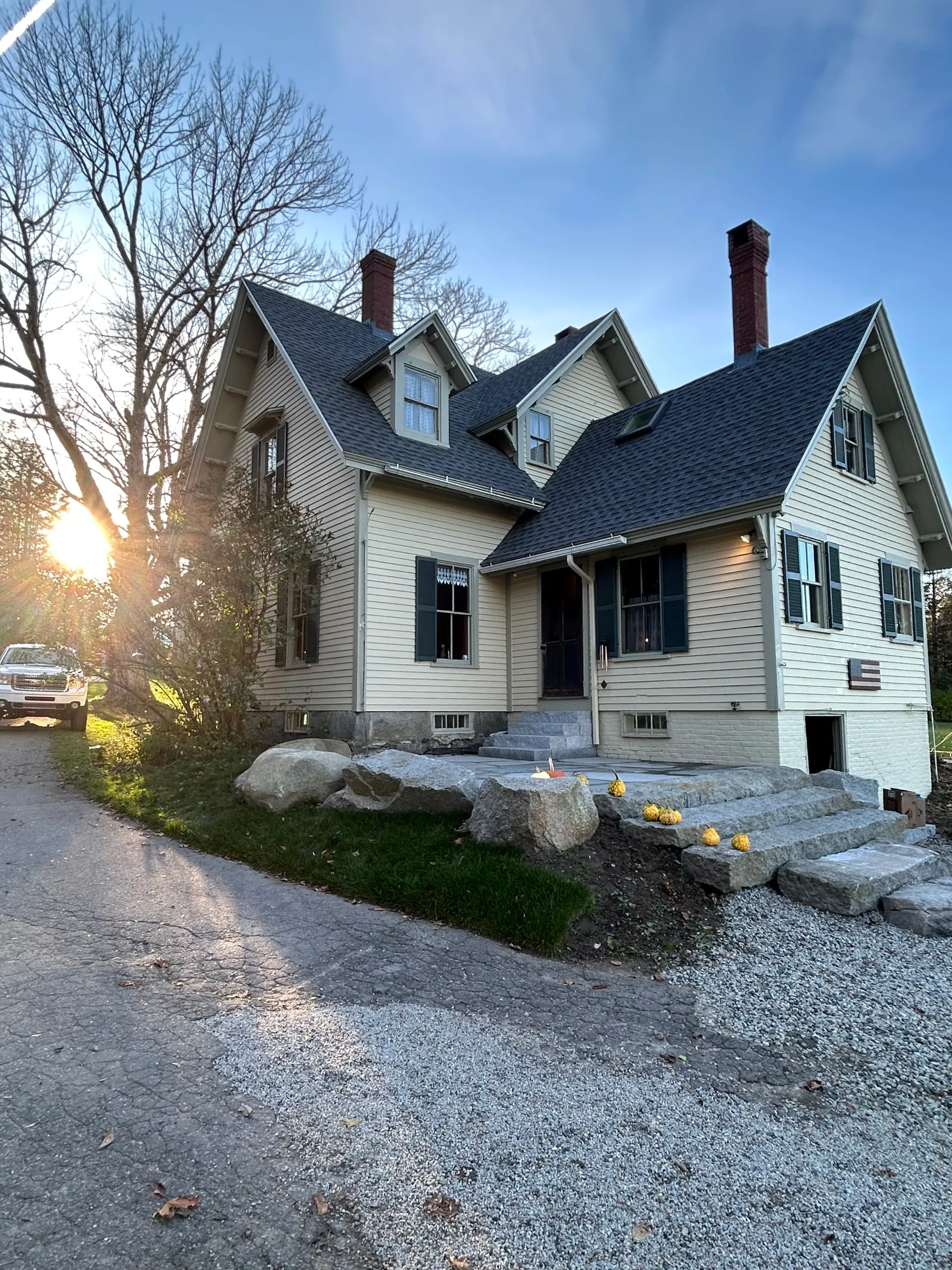 A large white house with a black roof and a car parked in front of it.