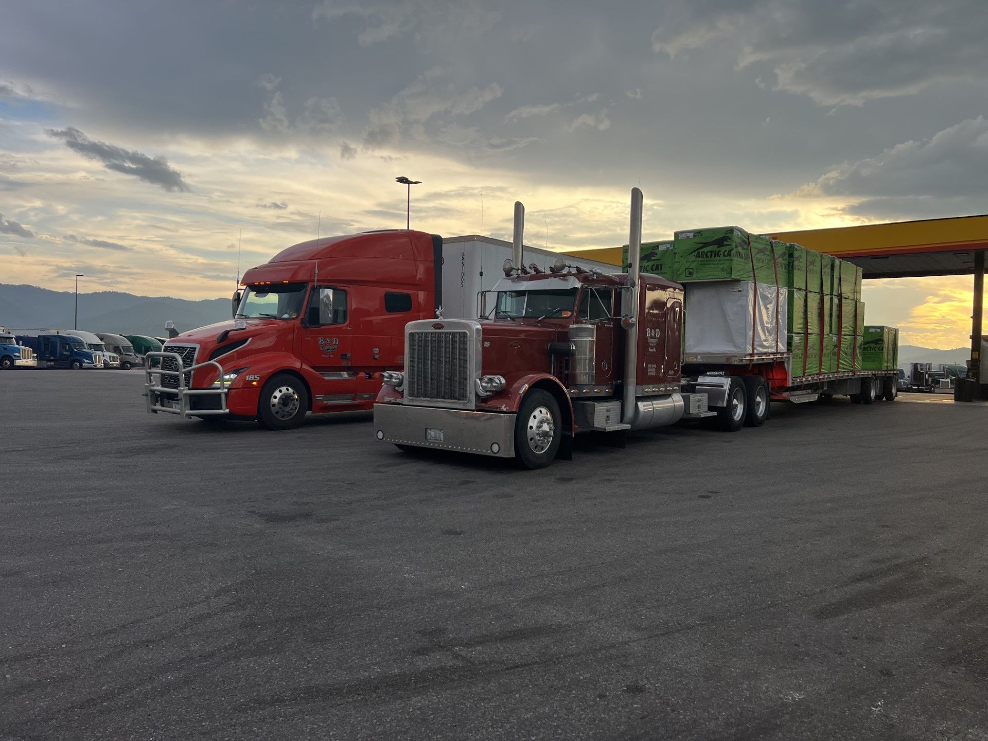 Two semi trucks are parked next to each other in a parking lot.