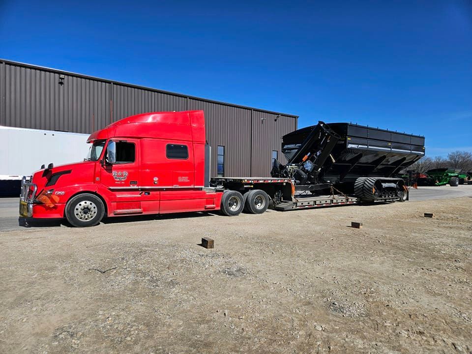 A red semi truck is parked in front of a building.