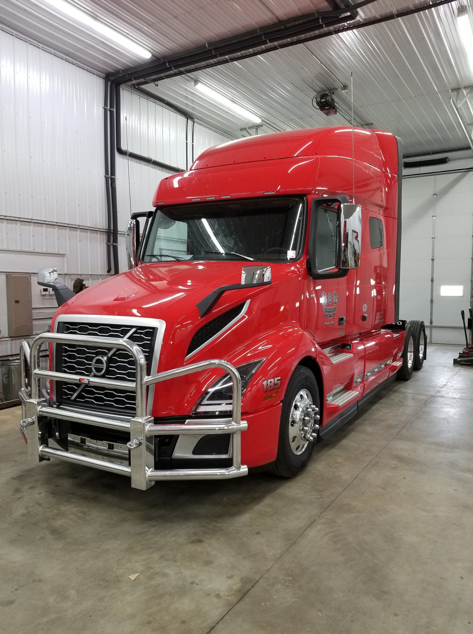 A red semi truck is parked in a garage.