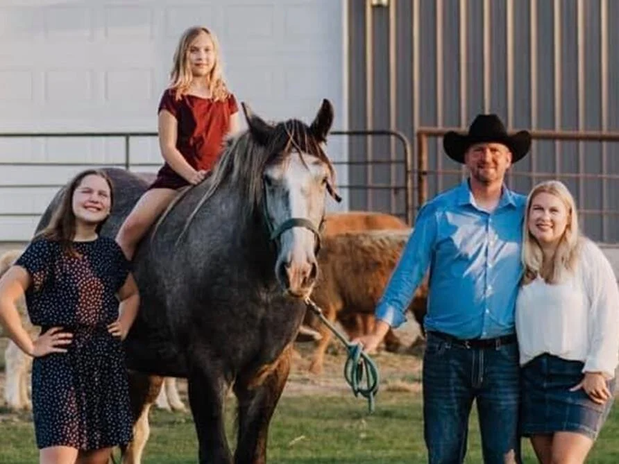 A family is posing for a picture with a horse.