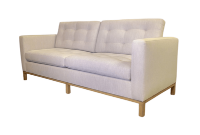 Beige two-seater sofa with square arms and button-tufted back on light wood legs.