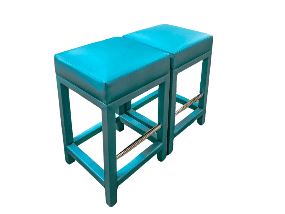 Two turquoise square stools with metal footrests.