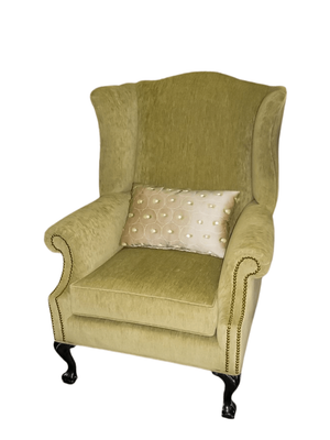Green wingback armchair with a decorative lumbar pillow.