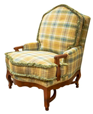 Armchair with yellow, blue, and green plaid fabric, wooden frame, and green fringe trim.