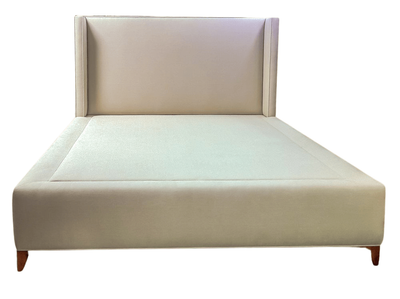 Cream upholstered bed frame with a tall headboard and low wooden legs.