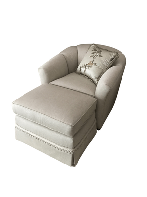Beige armchair with ottoman, floral pillow.