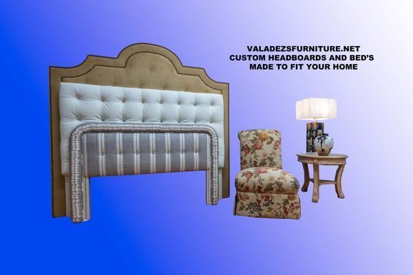 A bed headboard with tufted upholstered panels next to a chair, table, and lamp.