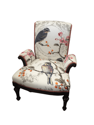 Upholstered armchair with bird and floral print; white background, dark wooden frame.