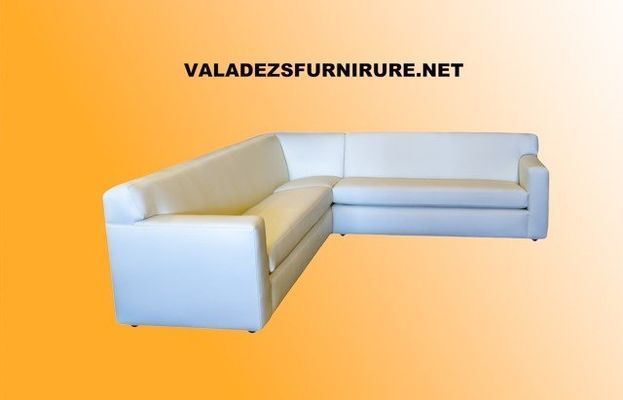 White L-shaped sectional sofa on an orange background. Website address is visible.