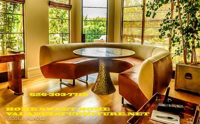 A stylish dining area with a curved booth in orange leather and a unique table with a gold base.
