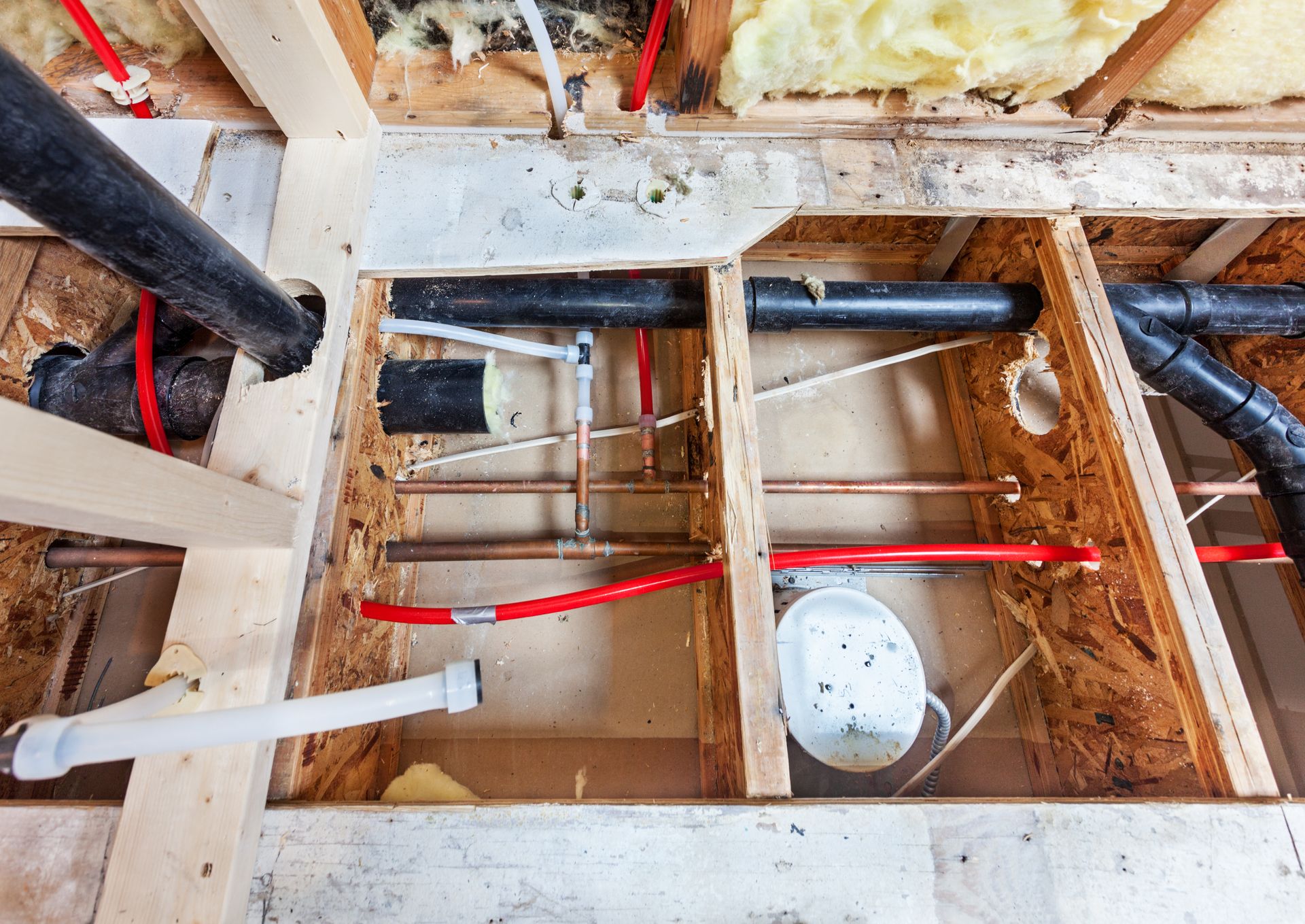 Exposed floor joists with plumbing and wiring in a construction renovation area