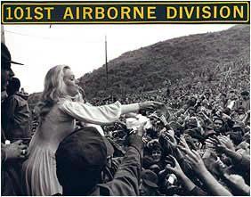 A black and white photo of a woman reaching out to a crowd of people.