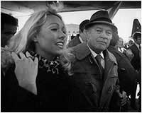 A black and white photo of a man and a woman standing next to each other.