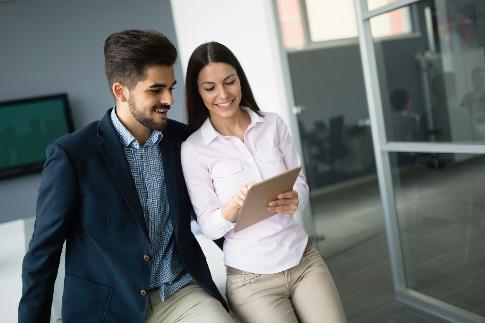 A man and a woman are looking at a tablet together.