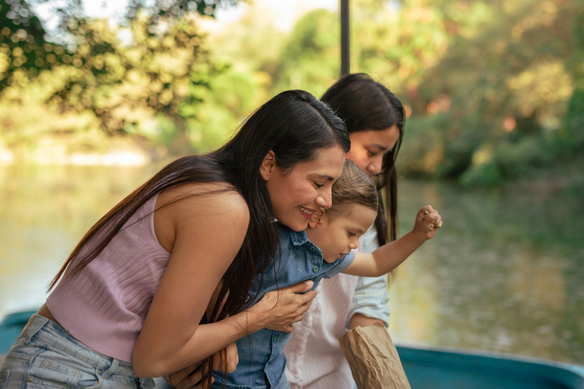 Two women and a child are sitting in a boat on a lake.