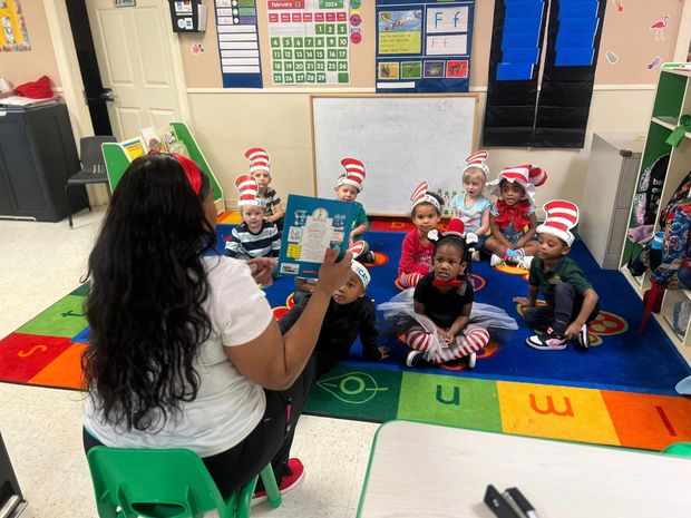 A woman is reading a book to a group of children in a classroom.