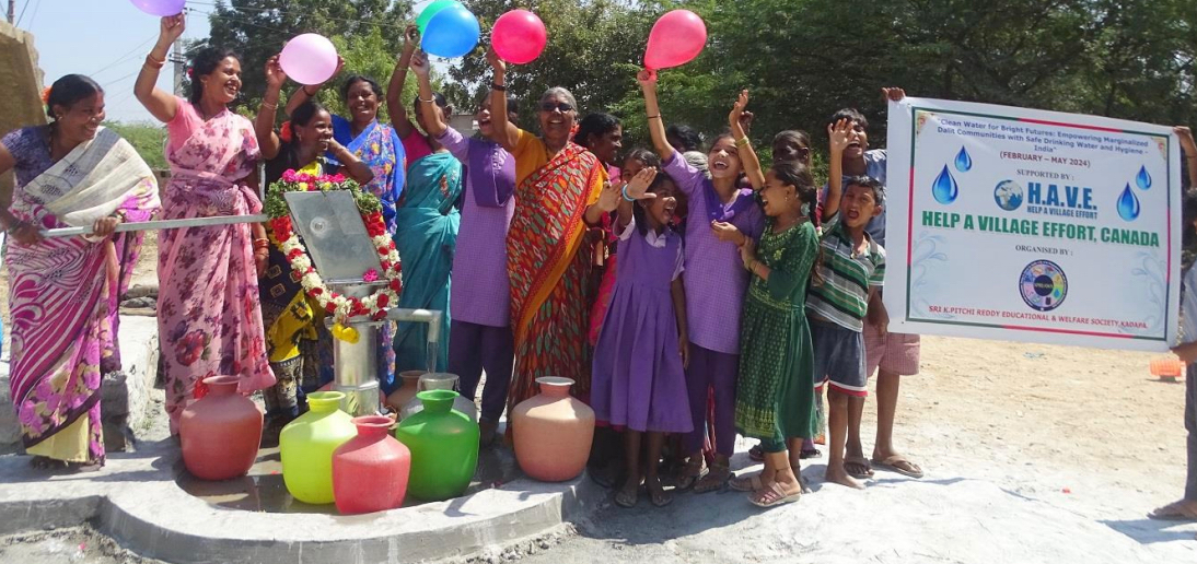 Group of women and children celebrating a new water well, holding balloons and raising their hands.