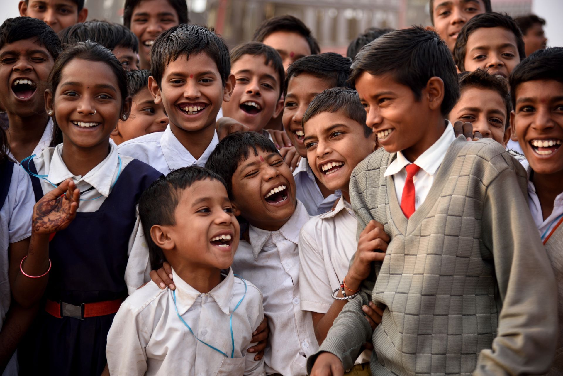 Smiling schoolchildren in India, laughing together outdoors.