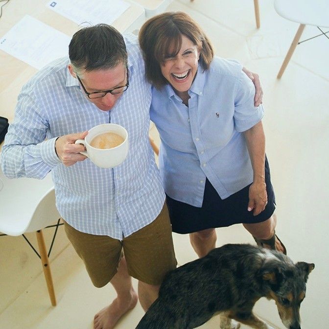 A man is holding a cup of coffee next to a woman and a dog