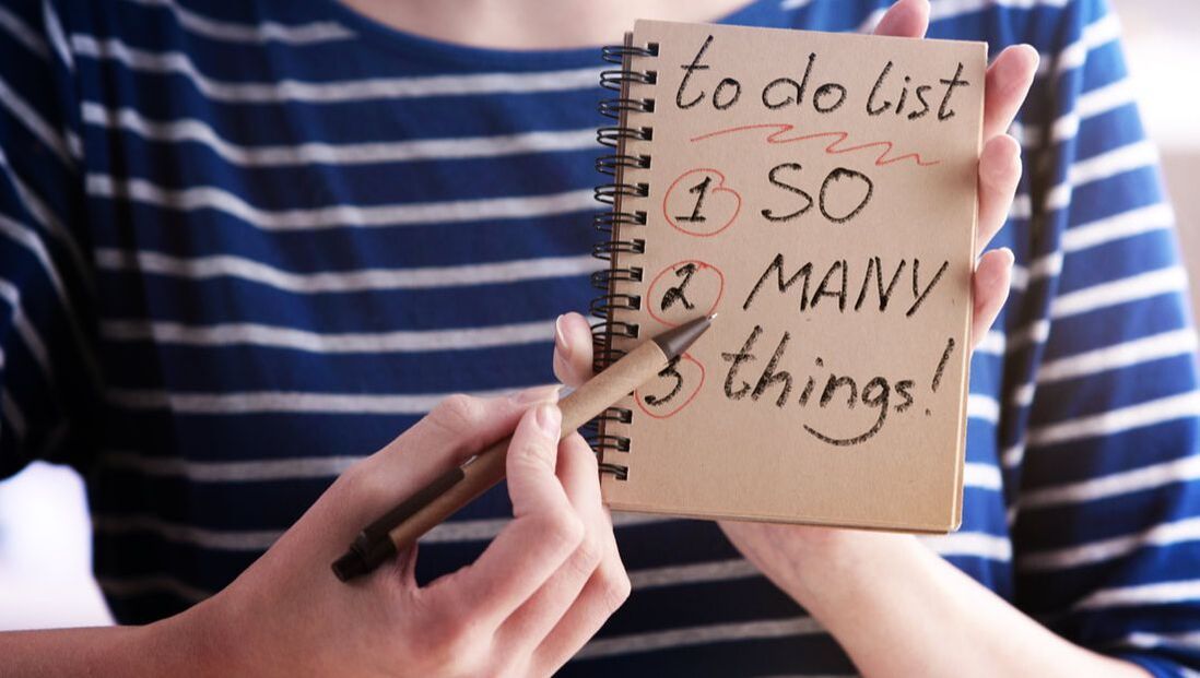 A woman is holding a notebook with a to do list written on it.
