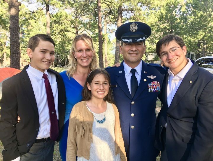 a man in a military uniform poses with his family