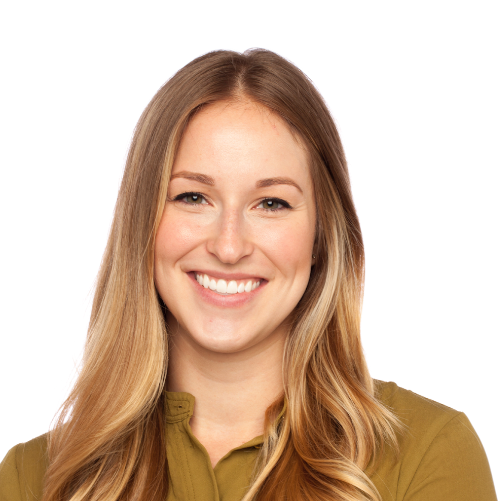 A woman with long blonde hair is smiling and wearing a green shirt