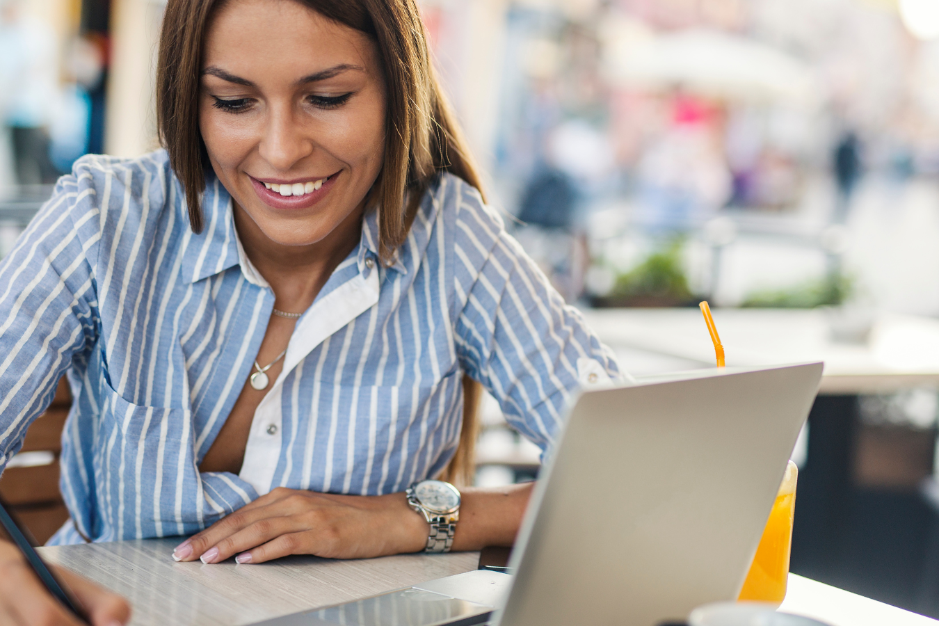 A woman is sitting at a table with a laptop and a pen.