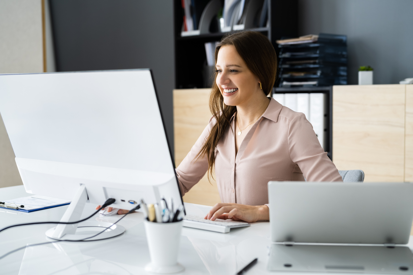 A woman is sitting at a desk in front of a computer.