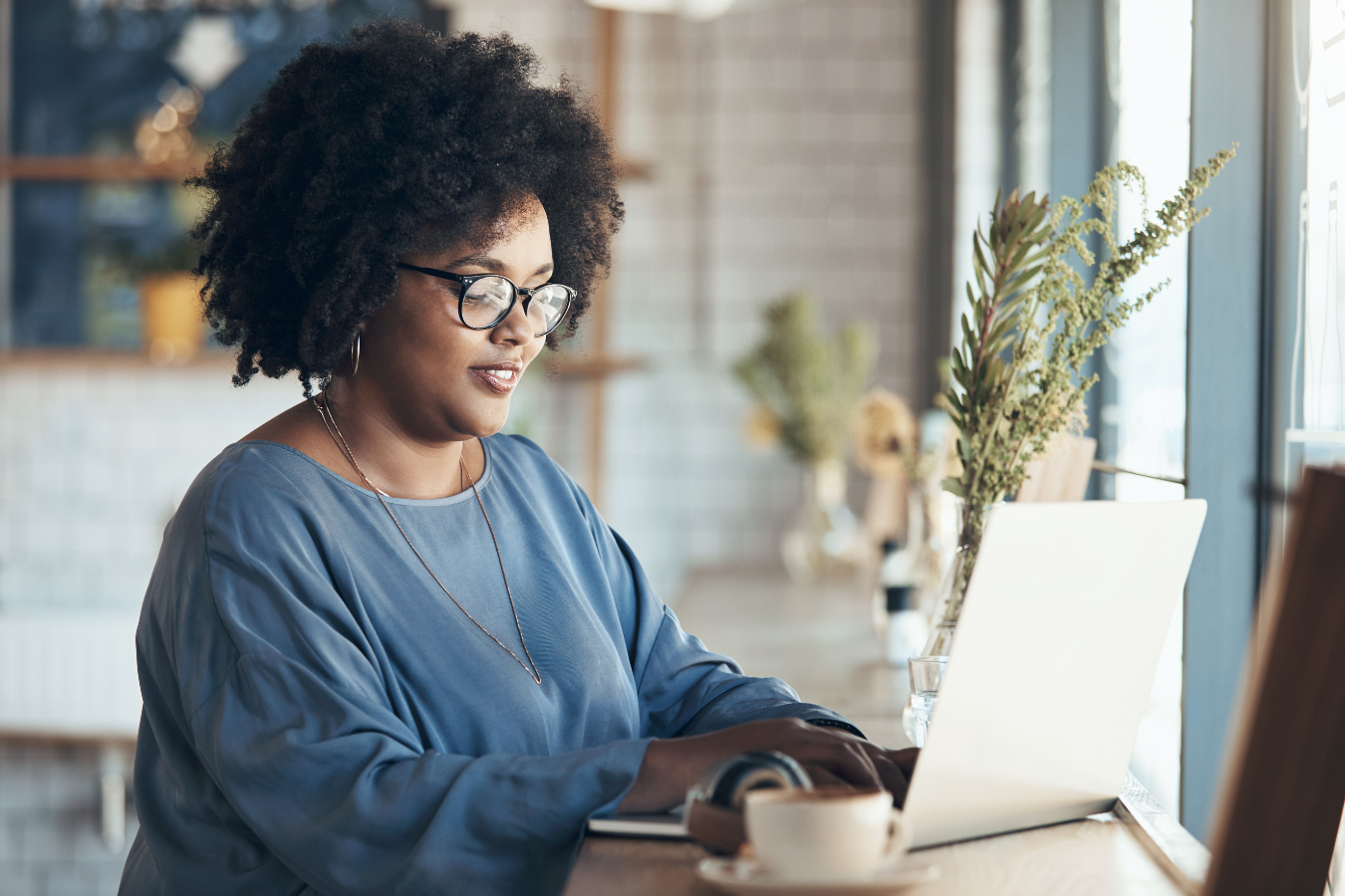 A woman is sitting at a table using a laptop computer.