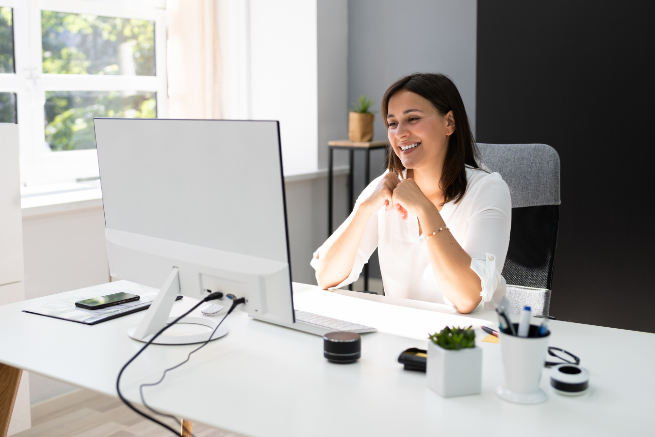 A woman smiles at her computer screen as she begins work as a virtual assistant | Freedom Makers