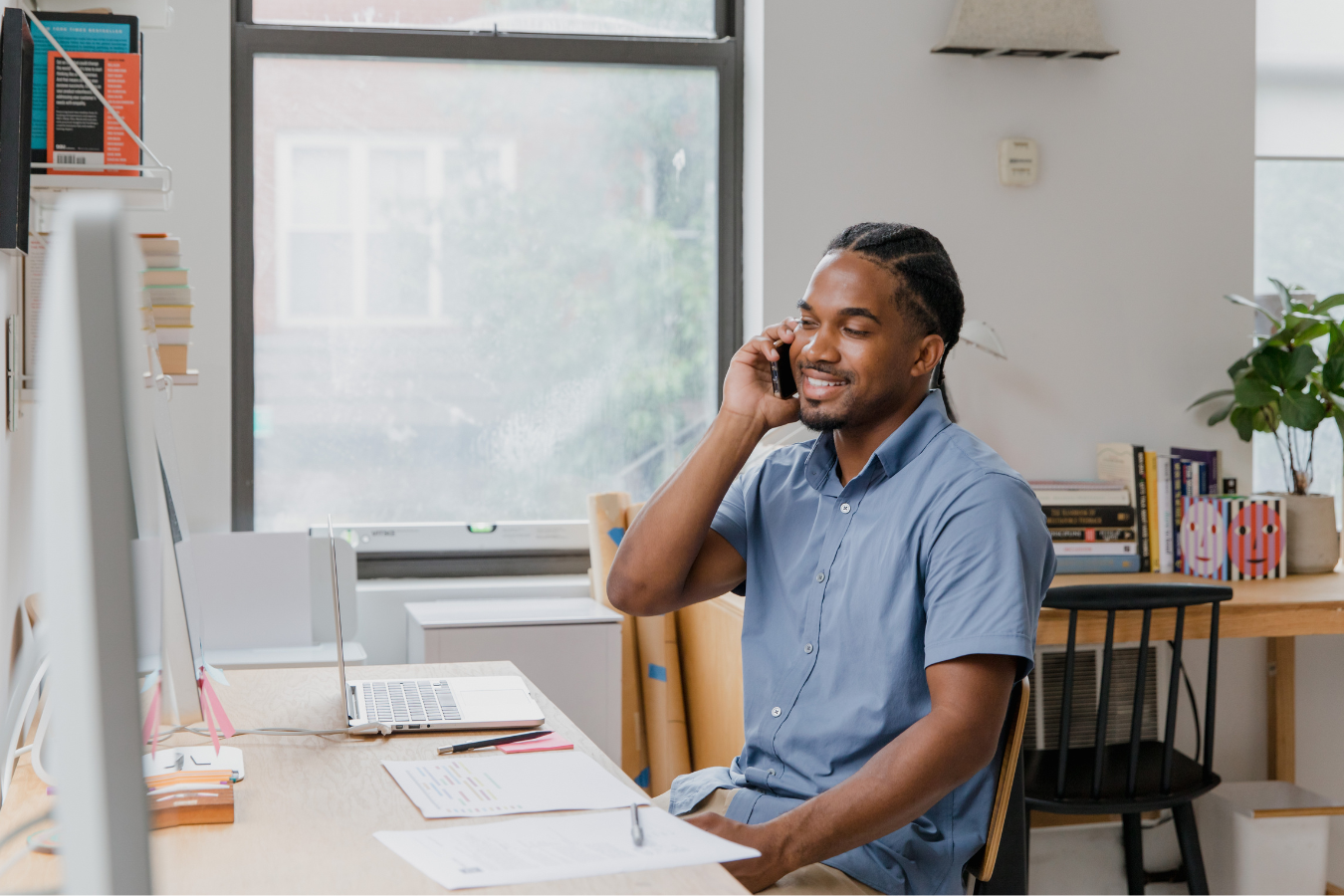 A man is sitting at a desk talking on a cell phone.