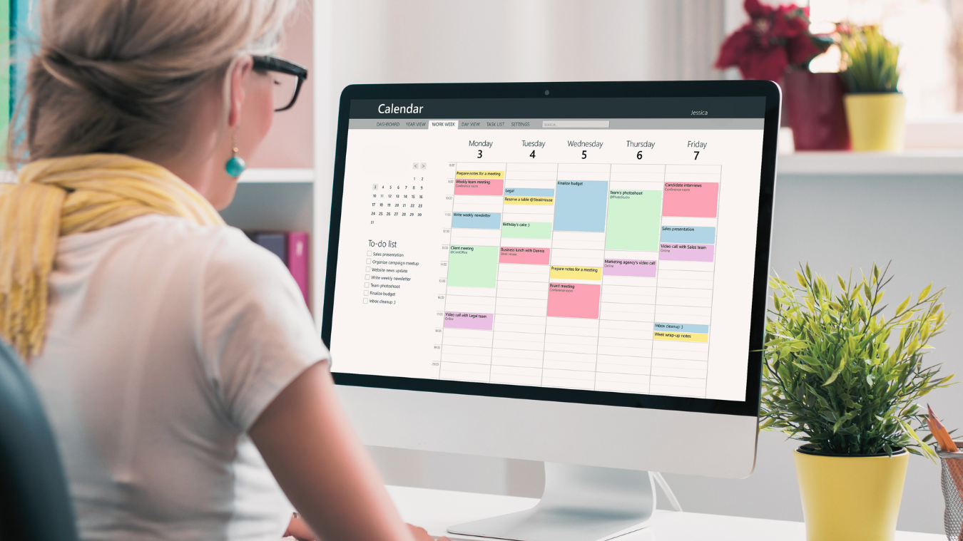 A woman manages a digital calendar from her desk.