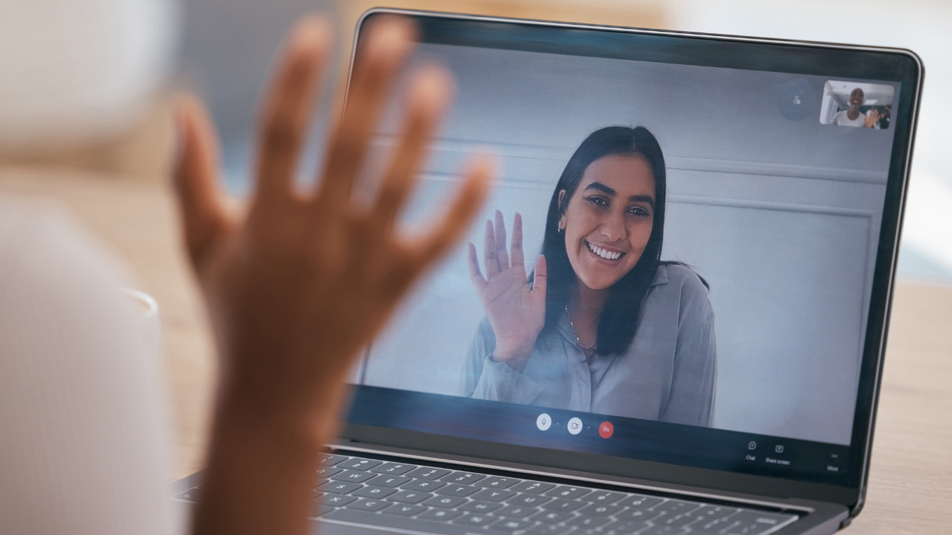 a woman is waving at another woman on a video call on a laptop