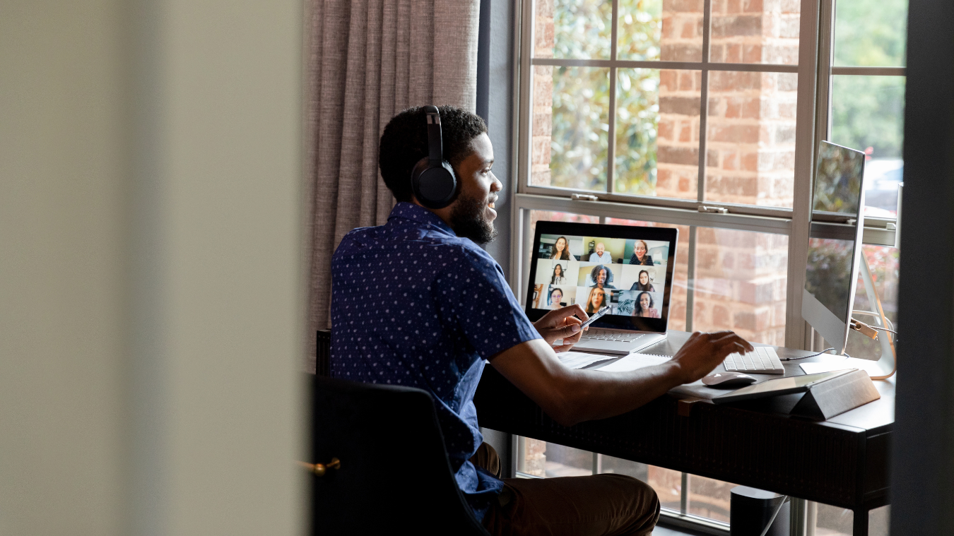 A man sits on his computer and works with his remote team members on the screen.