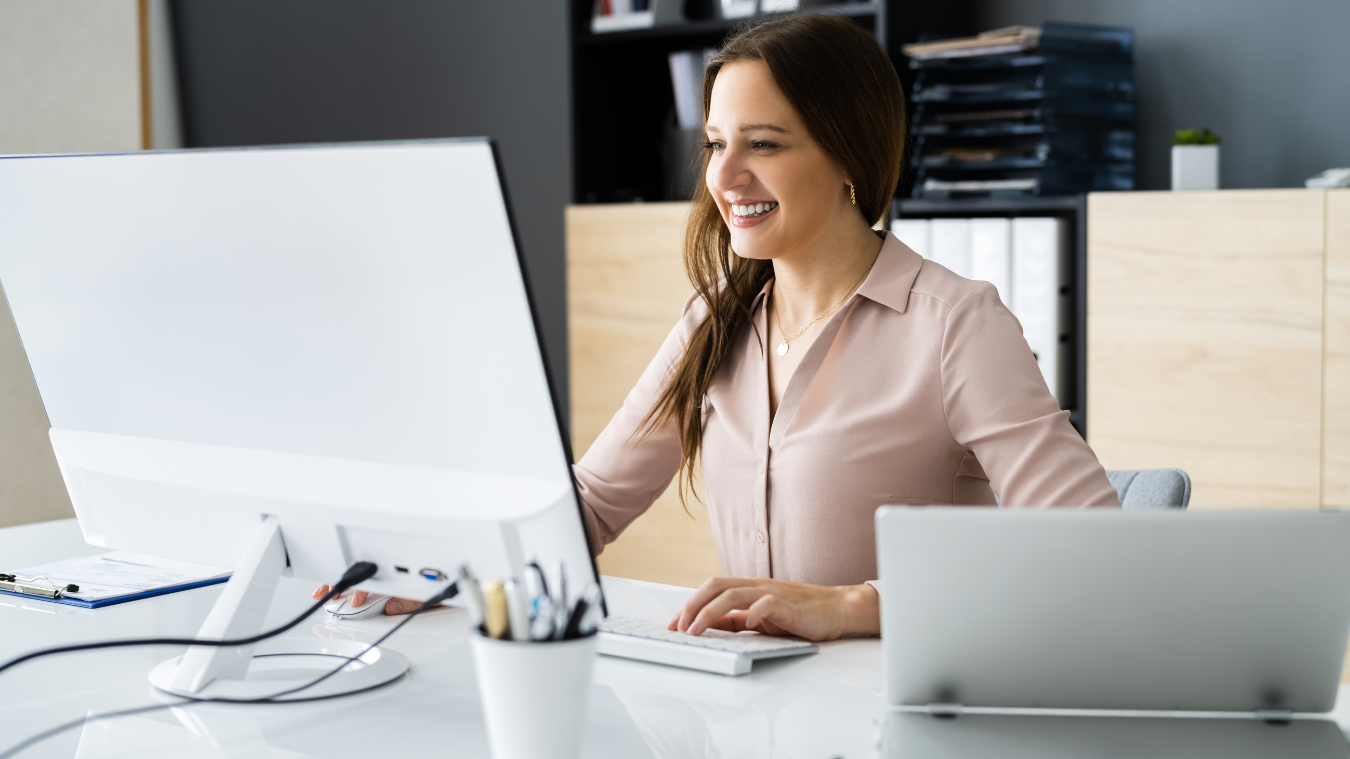 A woman is sitting at a desk in front of a computer.