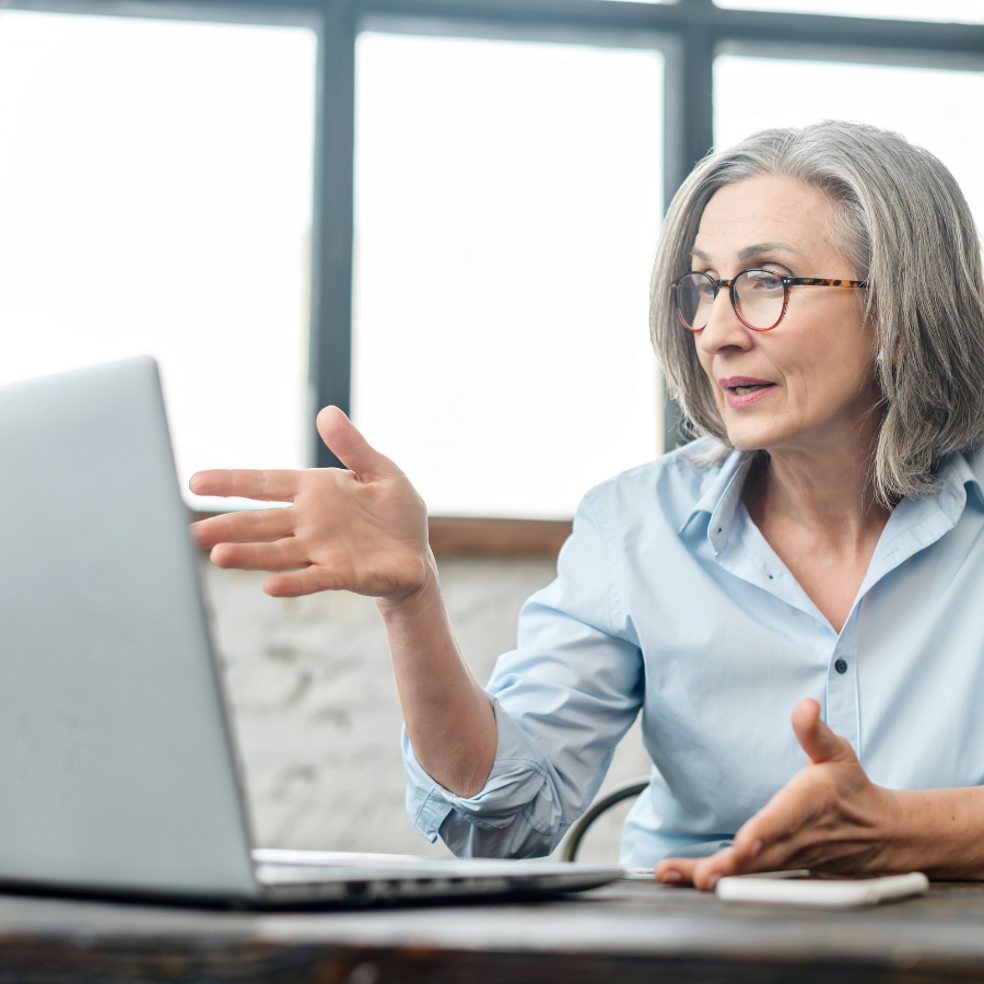 A woman is sitting at a desk in front of a laptop computer.