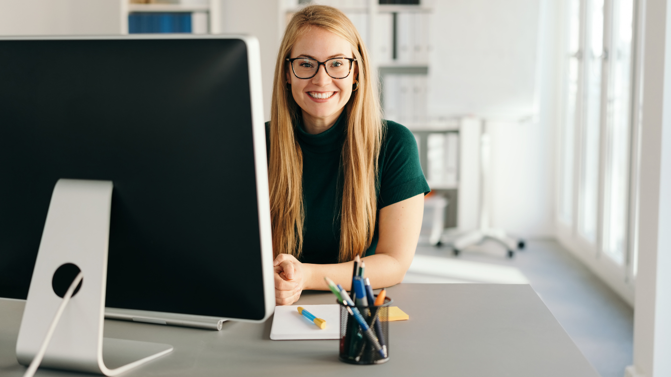 A woman is sitting at a desk in front of a computer.