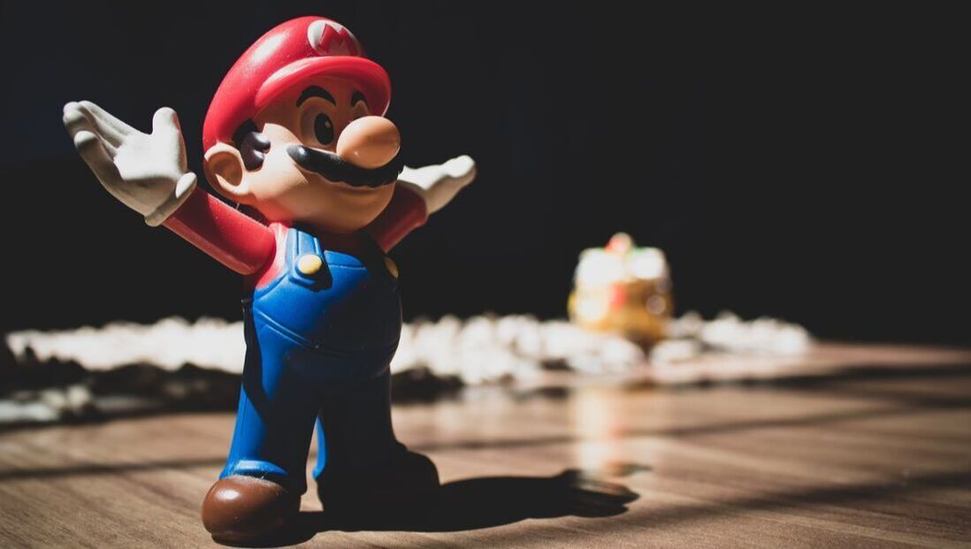 A mario figurine is standing on a wooden table.