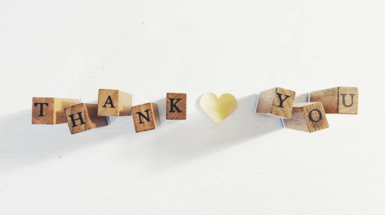The word thank you is written on wooden blocks with a heart in the middle.