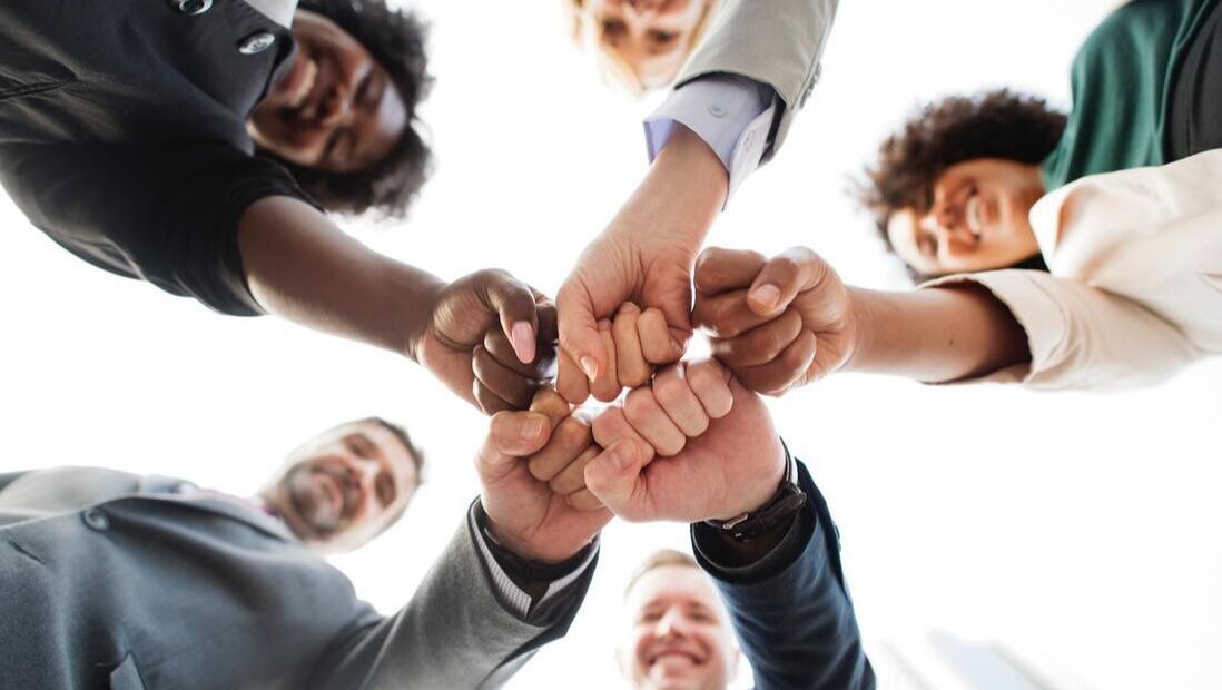 A group of people are putting their hands together in a circle.